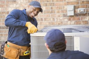 smiling-HVAC-technician-working-on-outdoor-unit